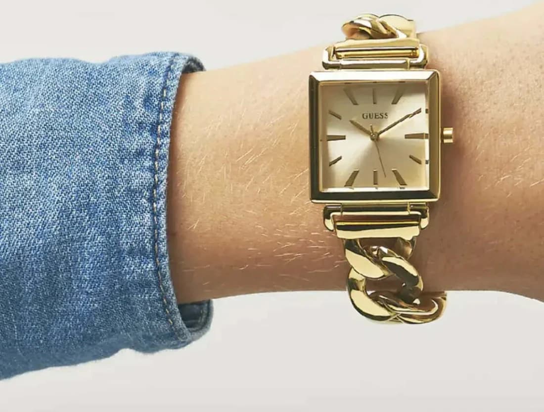 Visage cadran Guess W1029L2 avec cadran blanc laqué, index en bâton dorés, aiguilles bâton, guichet date à 3h et logo Guess à 12h
