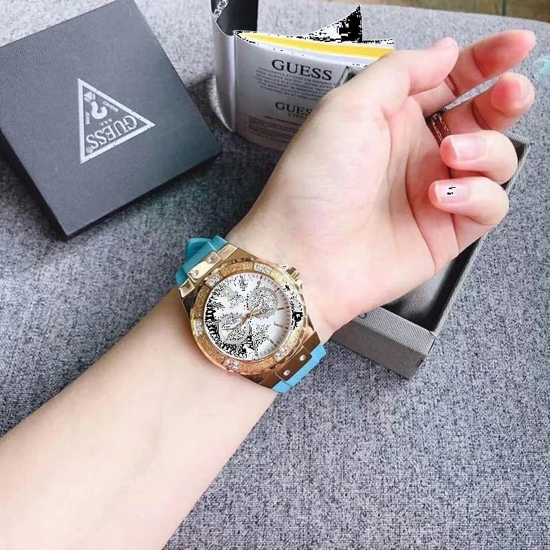 Visage cadran Guess W1053L6 avec index bâtons argentés et aiguilles luminescentes sur fond turquoise, date à 3h